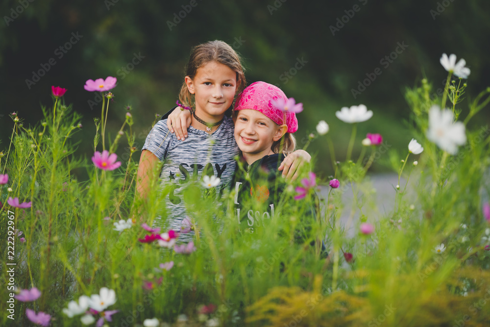 Portrait of two young girls in wild flower meadow looking at camera Portrait of two young girls in wild flower meadow looking at camera