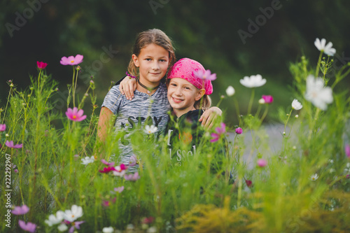 Portrait of two young girls in wild flower meadow looking at camera