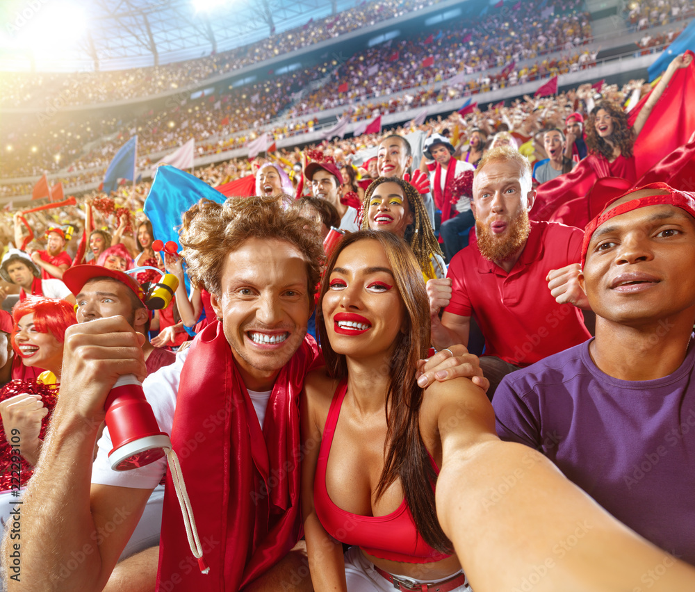 Young sport supporter happy fans at stadium. Beautiful man and woman support the team during the match and making selfie photo Stock | Adobe