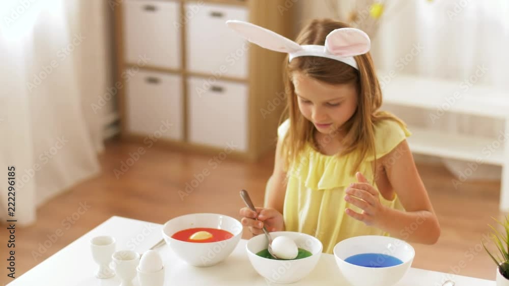 easter, holidays and people concept - happy girl wearing bunny ears headband coloring eggs by liquid dye at home easter, holidays and people concept - happy girl wearing bunny ears headband coloring eggs by liquid dye at home