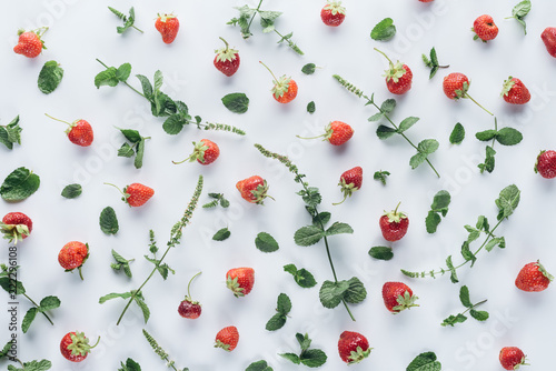 top view of fresh strawberries with mint leaves on white tabletop
