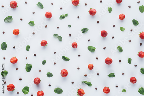 top view of ripe strawberries with mint leaves and coffee beans on white tabletop