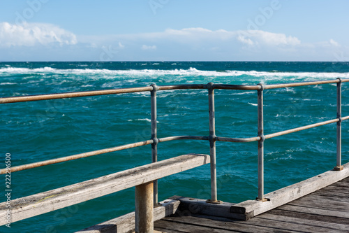 A bench seat on the Port Noarlunga Jetty looking out to the rough seas and reef in South Australia on 6th September 2018