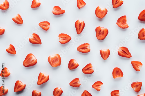 top view of fresh halved strawberries on white surface