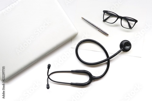 items doctor on desk , stethoscope , glasses , pen , laptop on white background