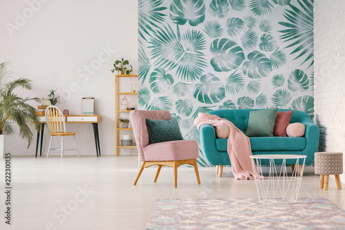 Принти на полотні Pink armchair next to blue settee in flat interior with green leaves wallpaper and table