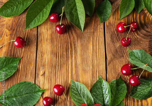 Berries of cherries and leaves against background of wooden boards