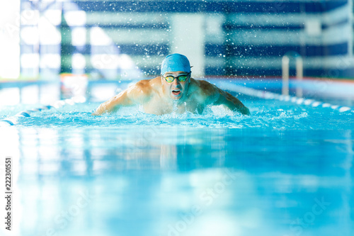 Image of sporty man sailing down path in pool in training