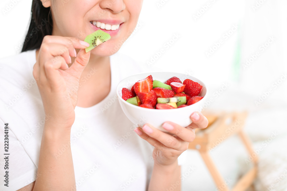 Woman eating healthy fruit salad at home, closeup Woman eating healthy fruit salad at home, closeup