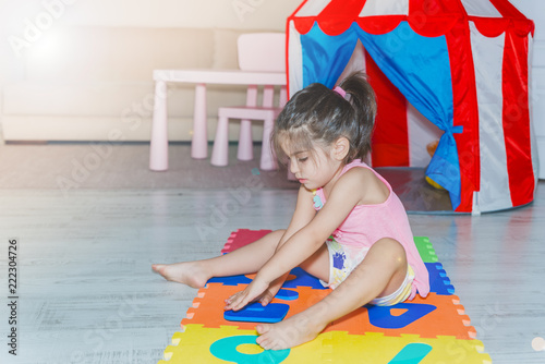 Little girl sits and holds colorful puzzle play mat