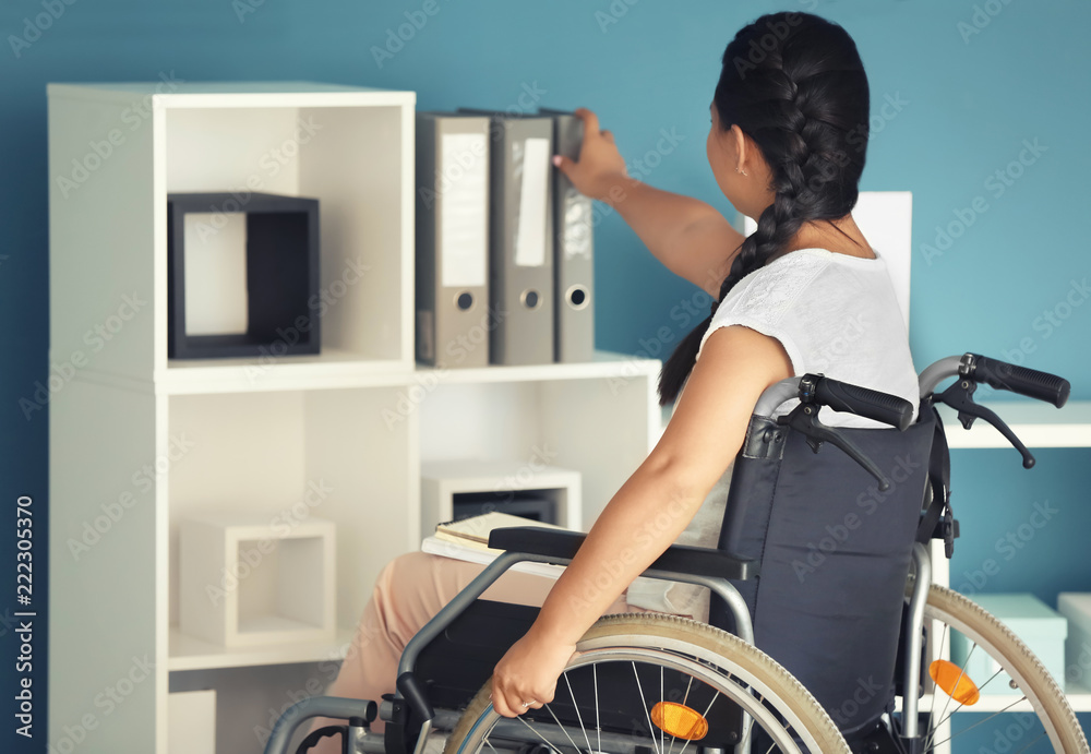Asian woman in wheelchair looking for documents in office Asian woman in wheelchair looking for documents in office