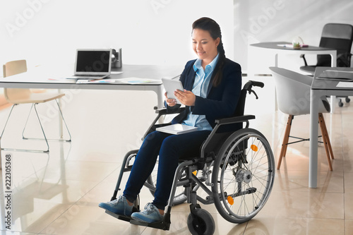 Asian woman in wheelchair working with tablet PC in office