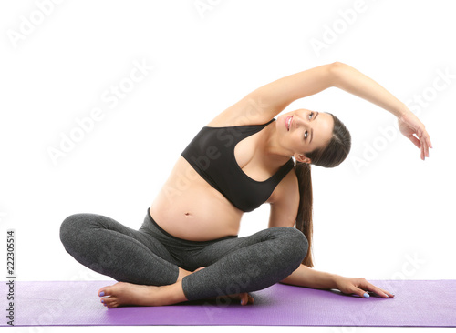 Young pregnant woman practicing yoga on white background