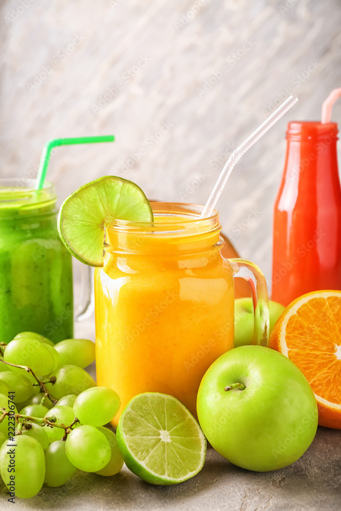 Glassware of tasty smoothies with fruits on grey table Glassware of tasty smoothies with fruits on grey table
