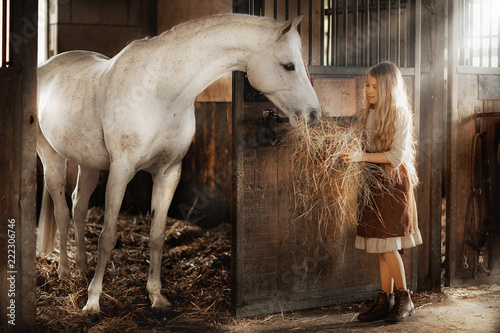 girl feeding horse in the stable photo