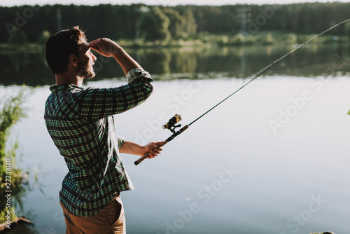 Man in Checkered Shirt Fishing on River in Summer.