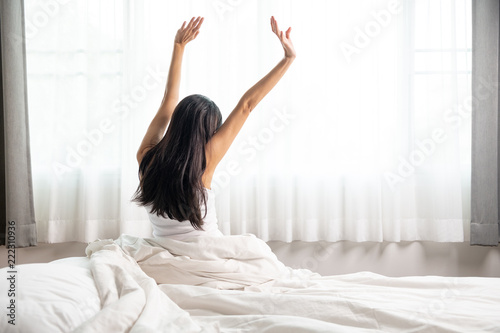 Woman waking up, stretching in bed.