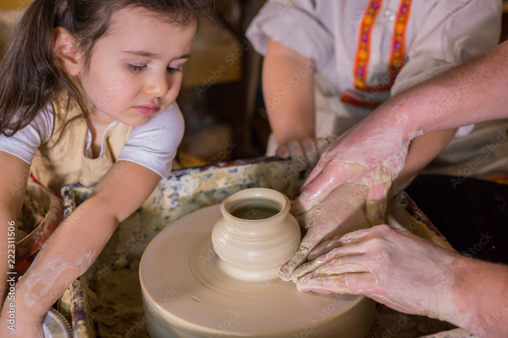 Pottery class and workshop: professional male potter working with children and showing how to make ceramic wares in pottery studio. Handmade, education and study concept
