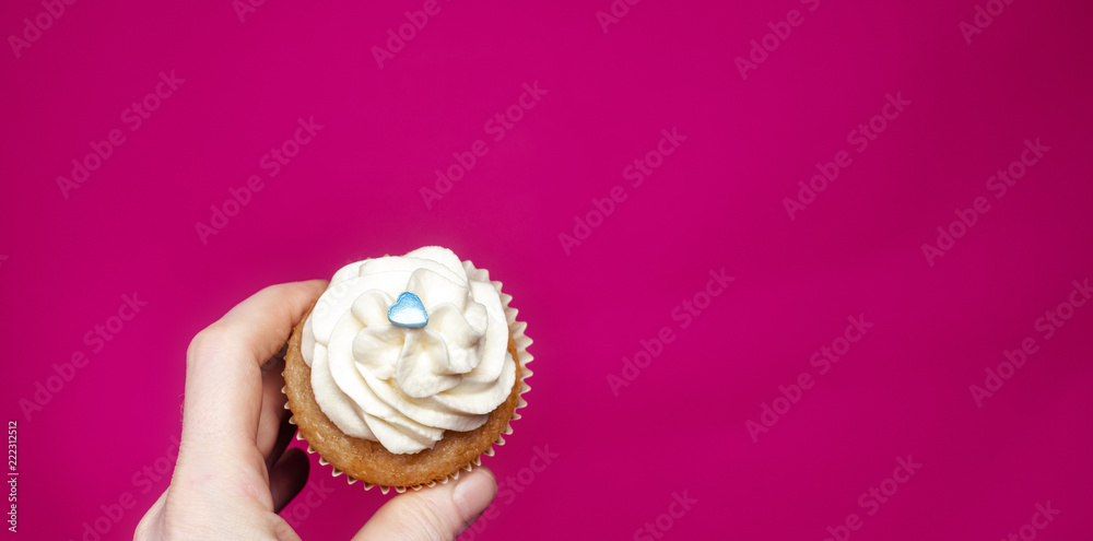 Cupcake with hand on pink background Cupcake with hand on pink background