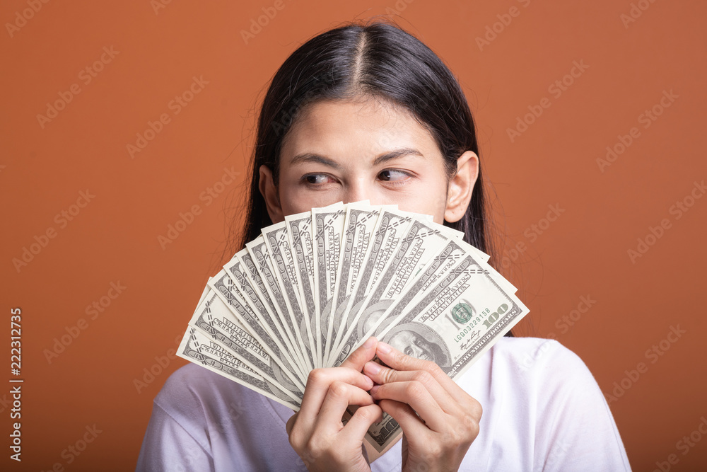 Woman holding cash notes isolated in orange background. Woman holding cash notes isolated in orange background.
