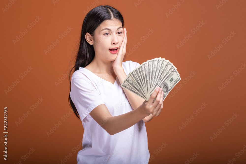 Woman holding cash notes isolated in orange background. Woman holding cash notes isolated in orange background.