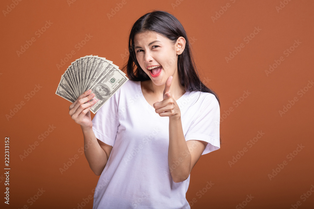 Woman holding cash notes isolated in orange background. Woman holding cash notes isolated in orange background.