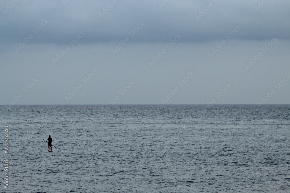 Man doing stand up paddle in the sea; cloudy day