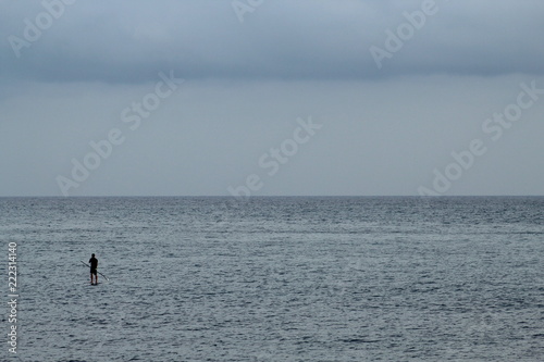 Man doing stand up paddle in the sea; cloudy day