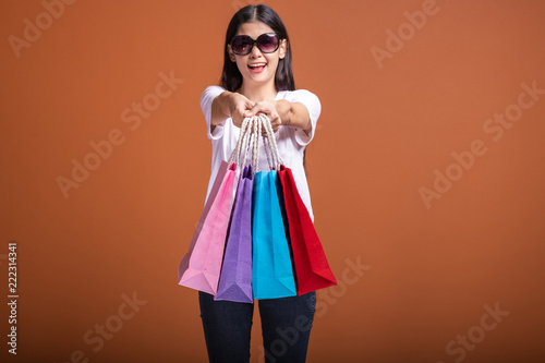 Woman holding shopping bag isolated in orange background.