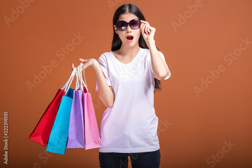 Woman holding shopping bag isolated in orange background.