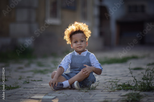 Fototapeta Naklejka Na Ścianę i Meble -  boy with curly hair sitting on the street road