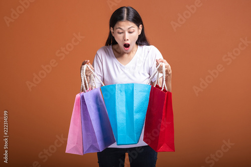 Woman holding shopping bag isolated in orange background.