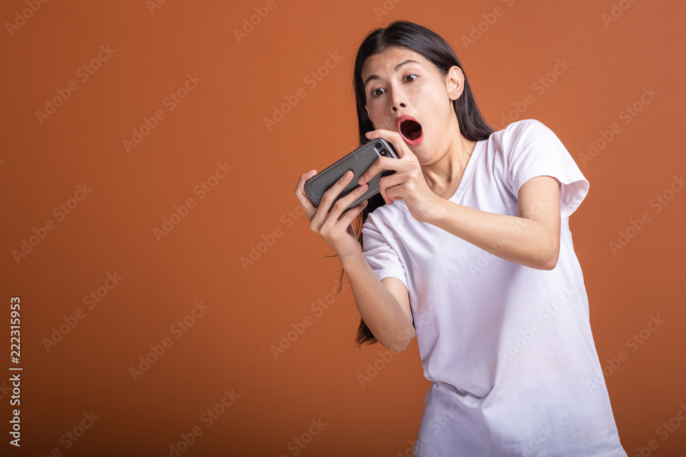 Woman playing mobile game isolated over orange background. Woman playing mobile game isolated over orange background.