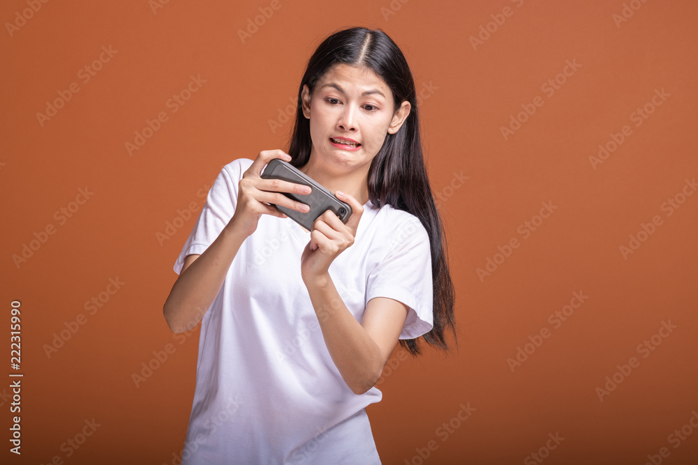 Woman playing mobile game isolated over orange background. Woman playing mobile game isolated over orange background.