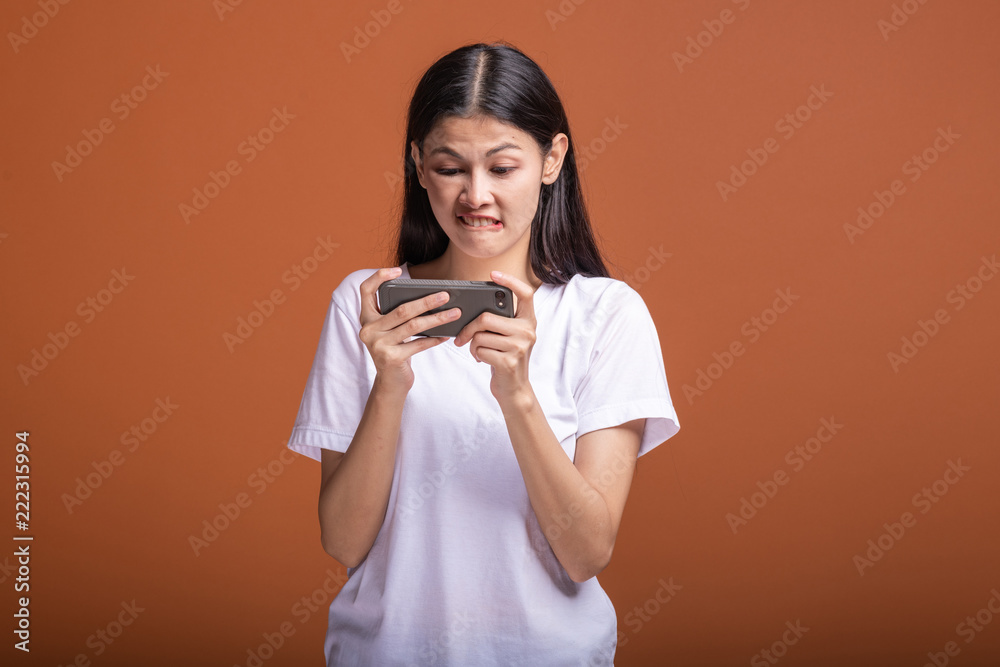 Woman playing mobile game isolated over orange background. Woman playing mobile game isolated over orange background.