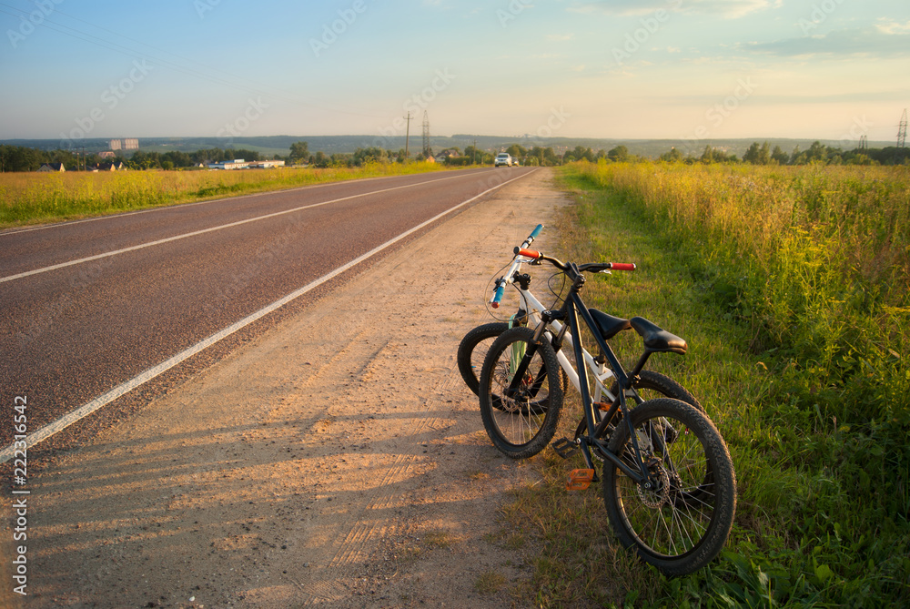 Bicycle tourism. Mountain bikes on a evening sunny light at the edge of the road, fields and landscape. Active freedom rest on vacation Bicycle tourism. Mountain bikes on a evening sunny light at the edge of the road, fields and landscape. Active freedom rest on vacation