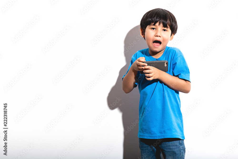 Young boy playing mobile game portrait in white background with hard light. Young boy playing mobile game portrait in white background with hard light.