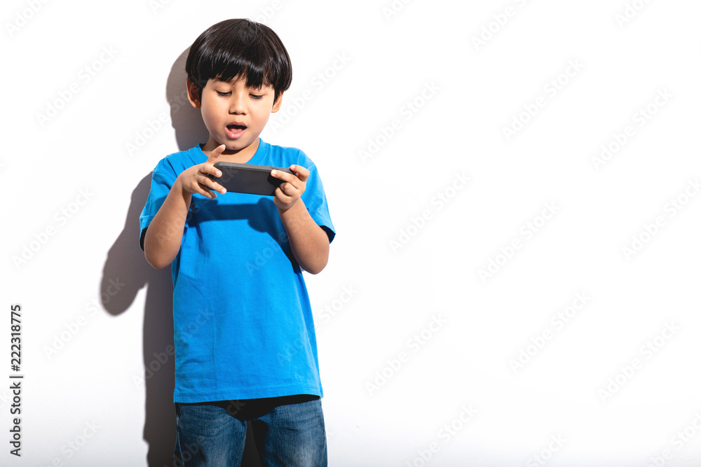 Young boy playing mobile game portrait in white background with hard light. Young boy playing mobile game portrait in white background with hard light.