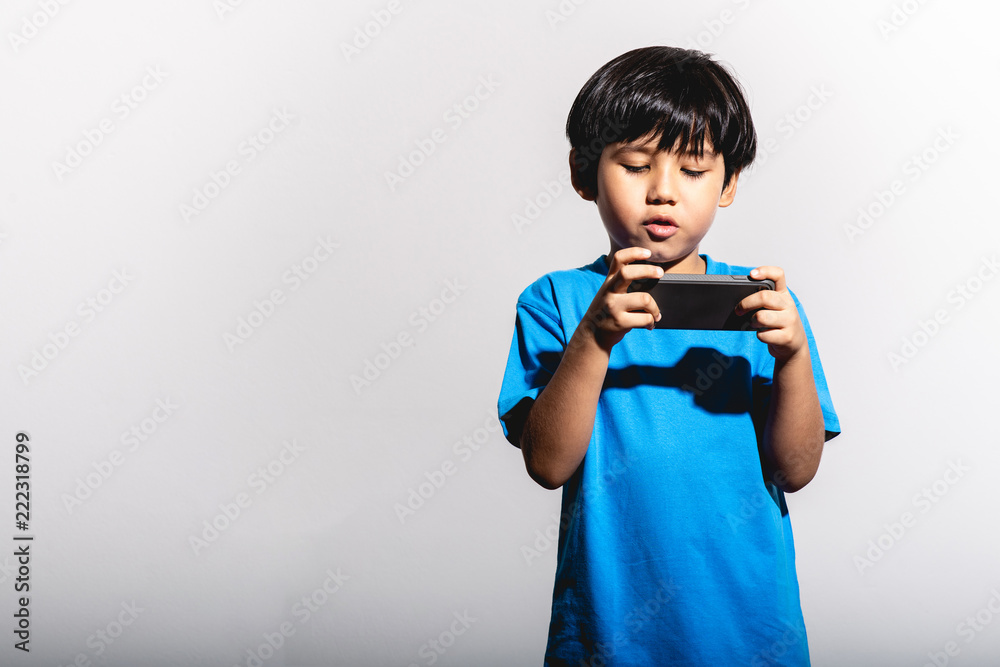 Young boy playing mobile game portrait in white background with hard light. Young boy playing mobile game portrait in white background with hard light.
