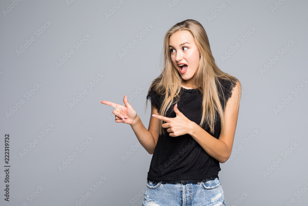 Beautiful young woman pointing to somewhere over a gray background Beautiful young woman pointing to somewhere over a gray background