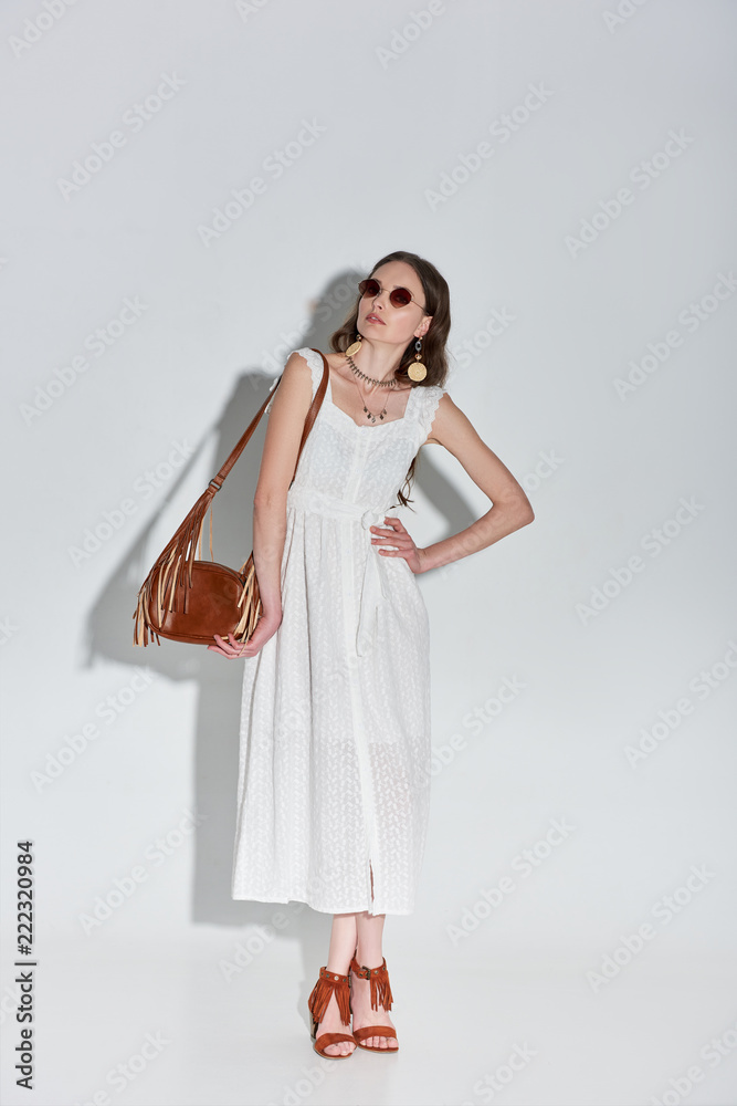 beautiful stylish woman in fashionable white dress posing with hand on waist on grey beautiful stylish woman in fashionable white dress posing with hand on waist on grey