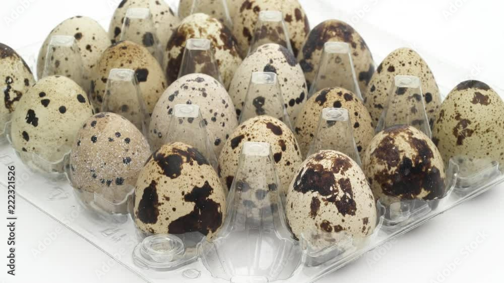 Male hands take out three quail eggs one by one from the opened transparent egg carton full of eggs. Isolated on white background. Close-up. Male hands take out three quail eggs one by one from the opened transparent egg carton full of eggs. Isolated on white background. Close-up.