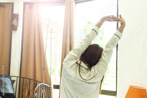 Back of view Woman stretching her arm after wake up on bed and looking outside windows in bedroom feeling so fresh and relax in the morning,Healthcare Concept