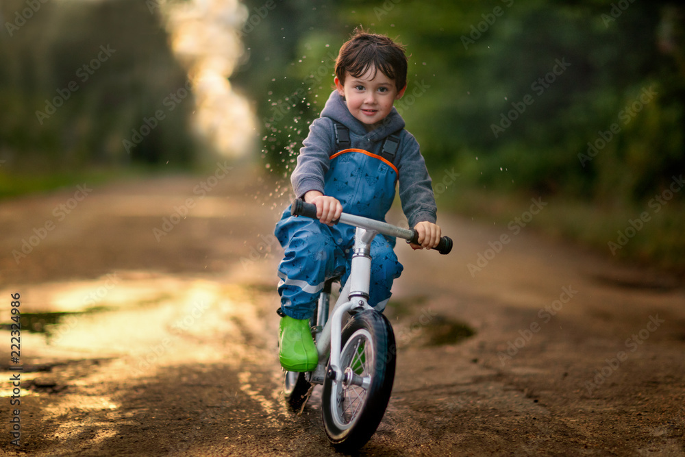boy riding bicycle through a puddle