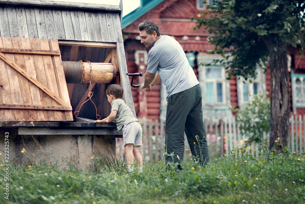 father and son getting water from well father and son getting water from well