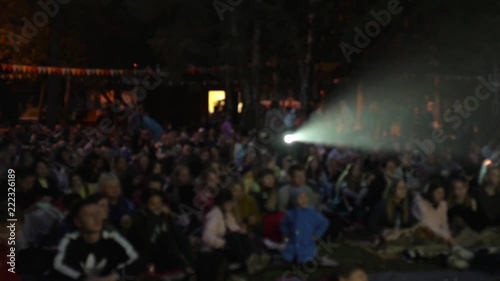 happy people watching a movie outdoors in the park at night, a group of people pulls hands up