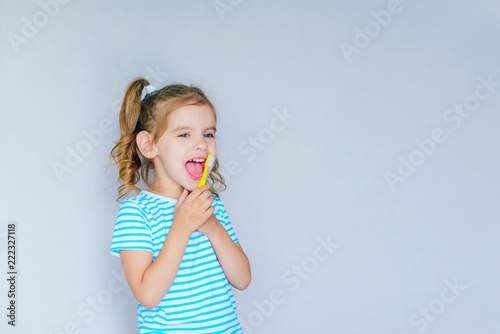 Beautiful baby girl brushing her teeth. Baby girl brushing her teeth and singing a favorite song.  Health care, dental hygiene, people and beauty concept. Mockup, free spase. Selective focus.  © NATALYA