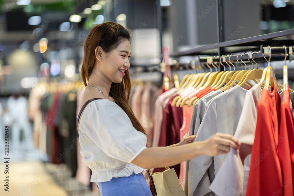 Beautiful Attractive Asian young woman choose cloth hang on shelf in Clothes store feeling so happiness and enjoy in shopping mall,Selective focus,Fashion and Shopping concept Beautiful Attractive Asian young woman choose cloth hang on shelf in Clothes store feeling so happiness and enjoy in shopping mall,Selective focus,Fashion and Shopping concept