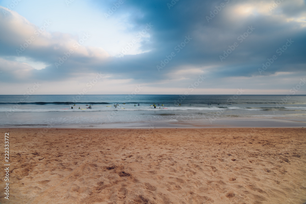 Blurry long exposure of unidentifiable surfers on a beach with fading light and copy space Blurry long exposure of unidentifiable surfers on a beach with fading light and copy space