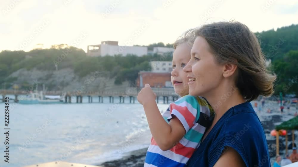 Beautiful woman with son looking over horison at the sea, windy weather Beautiful woman with son looking over horison at the sea, windy weather